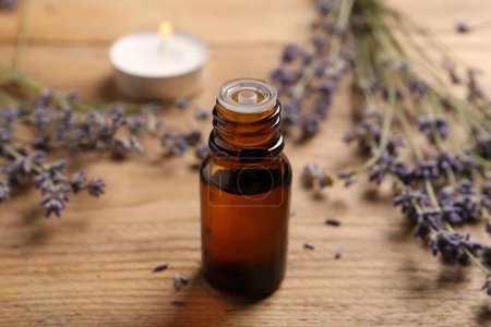 Photo for Bottle of essential oil and lavender flowers on wooden table - Royalty Free Image