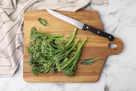 Photo for Fresh raw broccolini and knife on white marble table, flat lay. Healthy food - Royalty Free Image