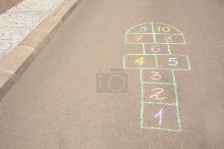 Photo for Hopscotch drawn with colorful chalk on asphalt outdoors. Space for text - Royalty Free Image