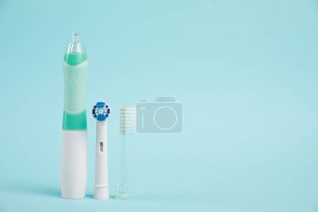 Photo for Electric toothbrush and replacement brush heads on light blue background, space for text - Royalty Free Image
