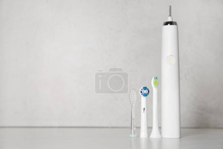 Photo for Electric toothbrush and replacement brush heads on light background, space for text - Royalty Free Image