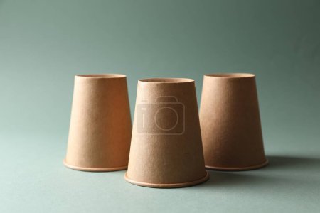 Téléchargez les photos : Trois tasses en papier sur fond olive pâle. Jeu de Thimblerig - en image libre de droit