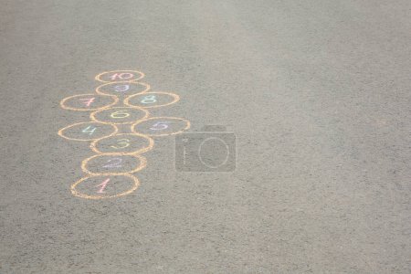 Photo for Hopscotch drawn with colorful chalk on asphalt outdoors, space for text - Royalty Free Image