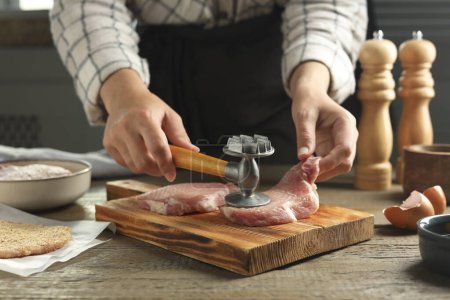 Téléchargez les photos : Femme cuisine schnitzel à la table en bois, gros plan - en image libre de droit