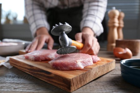 Téléchargez les photos : Femme cuisine schnitzel à la table en bois à l'intérieur, mise au point sélective - en image libre de droit