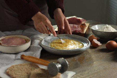 Téléchargez les photos : Femme cuisine schnitzel à la table en bois à l'intérieur, gros plan - en image libre de droit