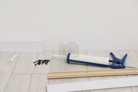 Photo for Plinths, caulking gun and screws on laminated floor in room - Royalty Free Image