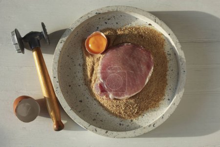 Téléchargez les photos : Schnitzel de cuisine. côtelette de porc cru, maillet de viande et ingrédients sur table en bois blanc, plat - en image libre de droit