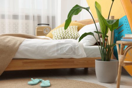 Photo for Large comfortable bed, SUP board and green houseplant in stylish bedroom. Interior element - Royalty Free Image