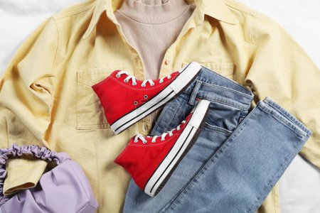 Foto de Par de elegantes zapatillas rojas, ropa y bolso en tela blanca, diseño plano - Imagen libre de derechos