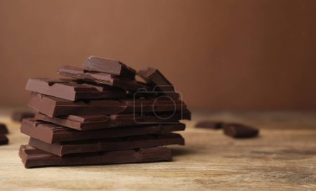 Los pedazos del chocolate sabroso sobre la mesa de madera, el primer plano. Espacio para texto