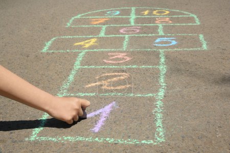 Photo for Child drawing hopscotch with colorful chalk on asphalt outdoors, closeup - Royalty Free Image