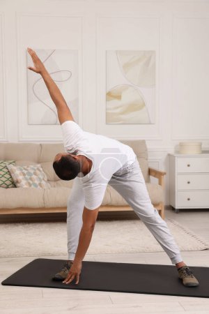 Hombre haciendo ejercicio matutino en la alfombra de fitness en casa