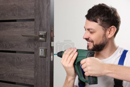 Téléchargez les photos : Travailleur avec pistolet à vis réparer serrure de porte à l'intérieur - en image libre de droit