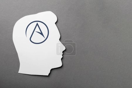 Téléchargez les photos : Papier tête humaine avec symbole d'athéisme sur fond gris, vue de dessus. Espace pour le texte - en image libre de droit