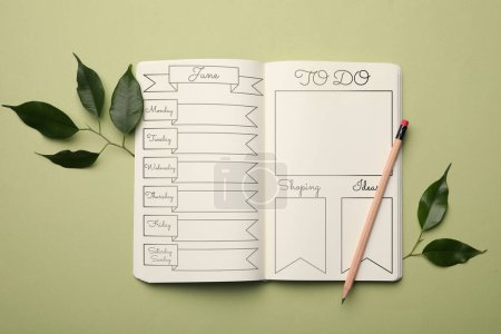 Autoorganización con diario bala. Cuaderno con listas de planificación vacías y hojas en la mesa verde, la puesta plana