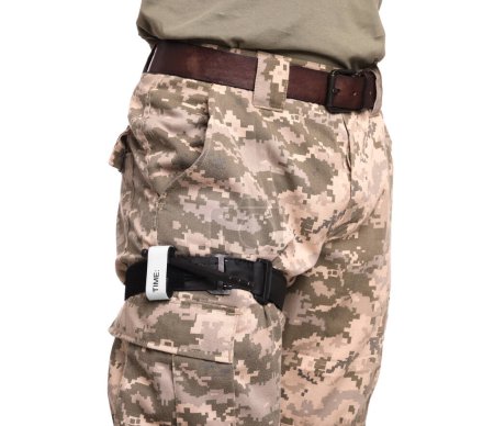 Foto de Soldado en uniforme militar con torniquete médico en pierna contra fondo blanco, primer plano - Imagen libre de derechos
