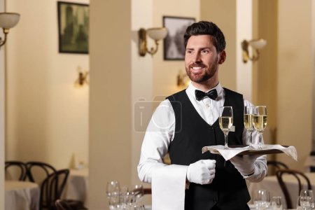 Butler holding tray with glasses of sparkling wine in restaurant. Space for text