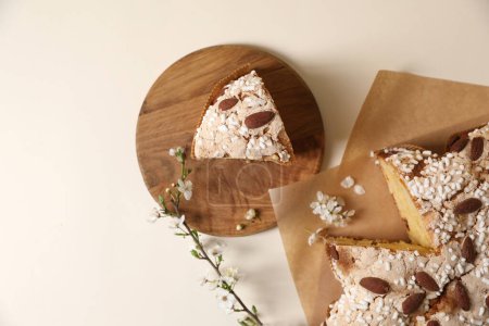Foto de Delicioso pastel de paloma de Pascua italiana cortada (Colomba di Pasqua tradicional) y la rama de floración en la mesa beige, la puesta plana. Espacio para texto - Imagen libre de derechos