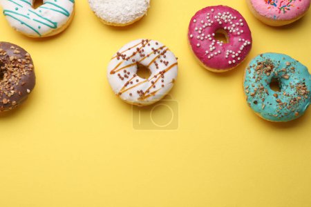 Tasty glazed donuts on yellow background, flat lay. Space for text