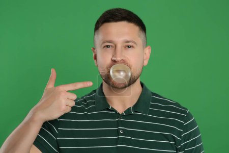 Photo for Handsome man blowing bubble gum on green background - Royalty Free Image