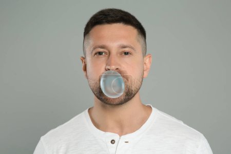 Téléchargez les photos : Handsome man blowing bubble gum on light grey background - en image libre de droit