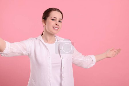 Téléchargez les photos : Femme heureuse invitant à venir dans sur fond rose - en image libre de droit