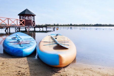 Photo for SUP boards with paddles on river shore - Royalty Free Image