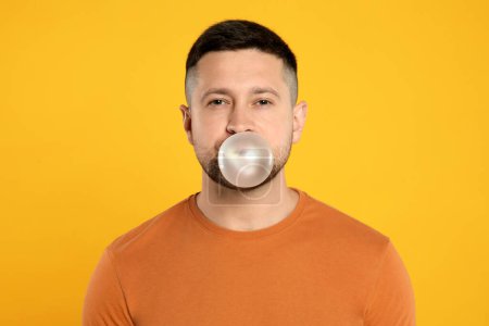Photo for Handsome man blowing bubble gum on orange background - Royalty Free Image