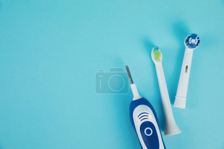 Photo for Electric toothbrush and replacement brush heads on light blue background, flat lay. Space for text - Royalty Free Image