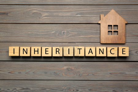 Photo for Word Inheritance made with cubes and house model on wooden background, flat lay - Royalty Free Image