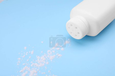 Photo for Bottle and scattered dusting powder on light blue background. Baby cosmetic product - Royalty Free Image