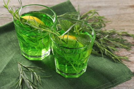 Photo for Glasses of refreshing tarragon drink with lemon slices on wooden table - Royalty Free Image