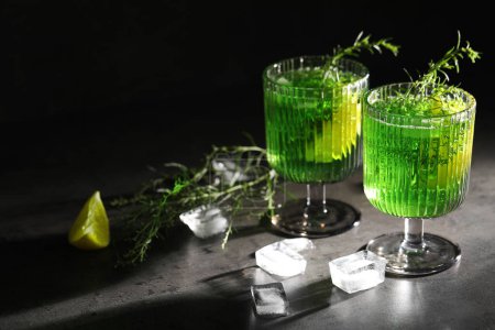 Photo for Glasses of homemade refreshing tarragon drink, ice cubes and sprigs on grey table. Space for text - Royalty Free Image