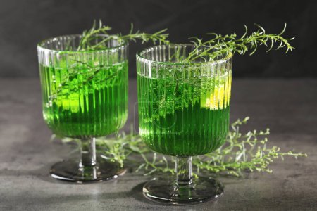 Photo for Glasses of homemade refreshing tarragon drink and sprigs on grey table, closeup - Royalty Free Image