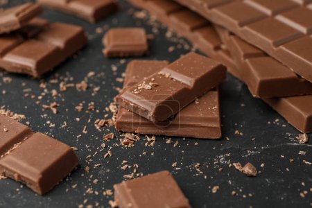 Téléchargez les photos : Morceaux de chocolat savoureux sur table noire, gros plan - en image libre de droit