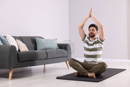 Man meditating at home, space for text