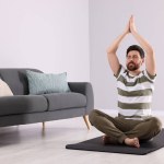 Man meditating at home, space for text