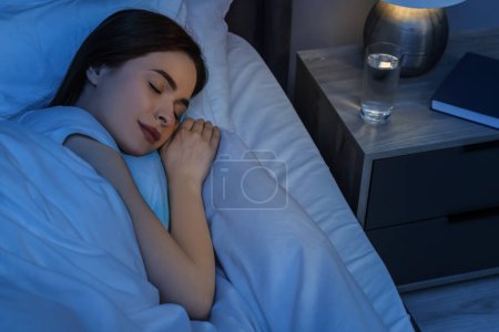 Foto de Hermosa mujer joven durmiendo en la cama por la noche - Imagen libre de derechos