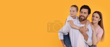 Téléchargez les photos : Joyeux famille avec enfant sur fond orange, espace pour le texte. Conception de bannière - en image libre de droit