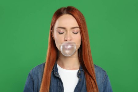 Téléchargez les photos : Belle femme soufflant gomme à bulles sur fond vert - en image libre de droit
