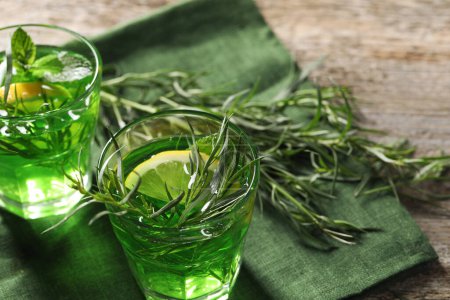 Photo for Glasses of refreshing tarragon drink with lemon slices on wooden table. Space for text - Royalty Free Image