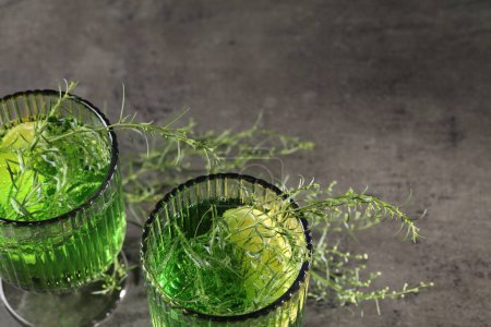 Photo for Glasses of homemade refreshing tarragon drink and sprigs on grey table, above view with space for text - Royalty Free Image