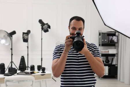 Téléchargez les photos : Jeune photographe professionnel avec appareil photo dans un studio photo moderne, espace pour le texte - en image libre de droit