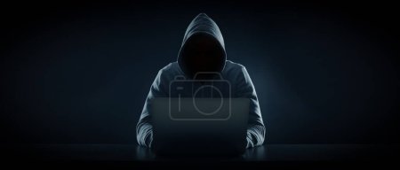 Téléchargez les photos : Homme anonyme dans la capuche à l'aide d'un ordinateur portable sur fond noir. Conception de bannière - en image libre de droit