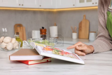Foto de Mujer con libro de recetas en la mesa en la cocina, primer plano - Imagen libre de derechos