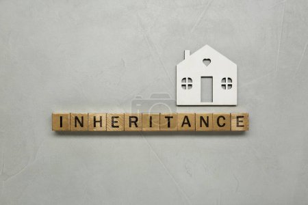 Photo for Word Inheritance made with wooden cubes and house model on grey background, flat lay - Royalty Free Image