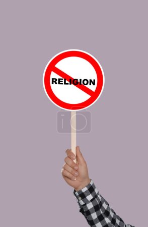 Foto de Concepto de ateísmo. Hombre sosteniendo la prohibición signo con la palabra tachada Religión sobre fondo de color - Imagen libre de derechos