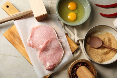 Téléchargez les photos : Côtelettes de porc crues, maillet de viande et ingrédients pour la cuisson de schnitzel sur table grise, plat - en image libre de droit