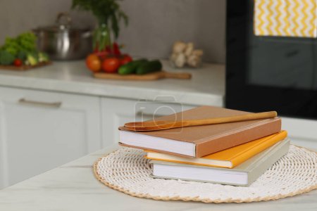 Foto de Libros de recetas y cuchara de madera sobre mesa de mármol blanco en la cocina, primer plano. Espacio para texto - Imagen libre de derechos